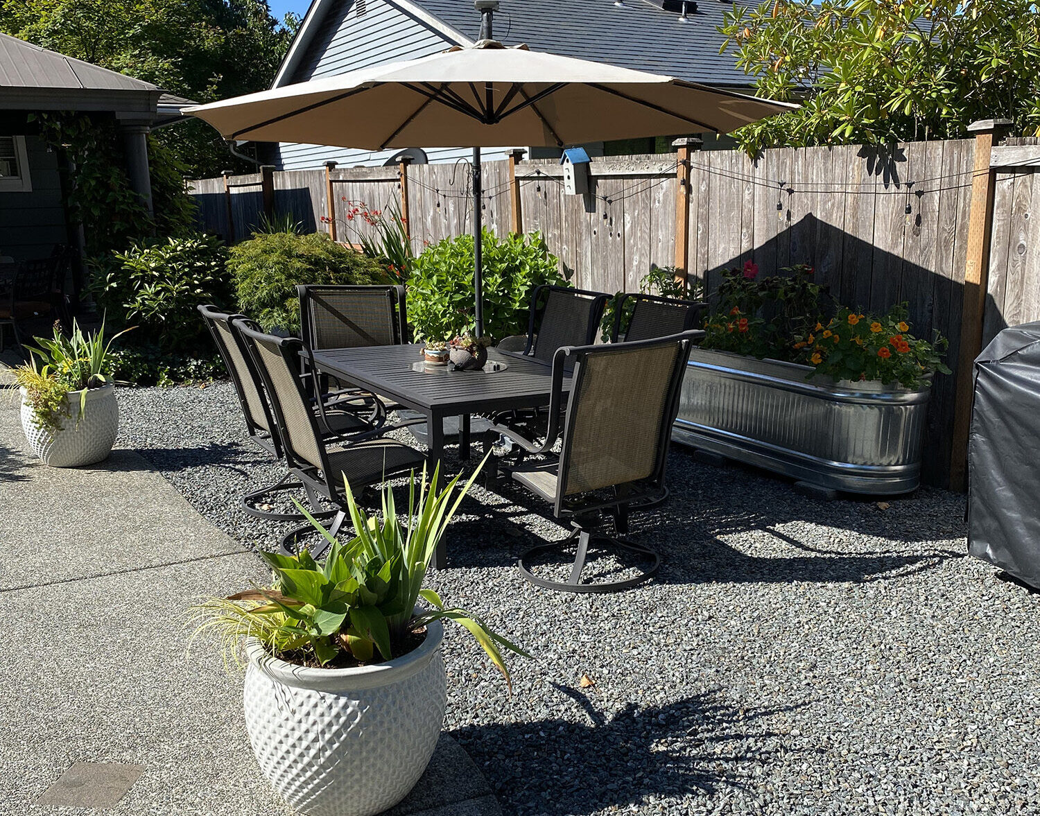Photo of a backyard with potted plants, furniture, and gravel.