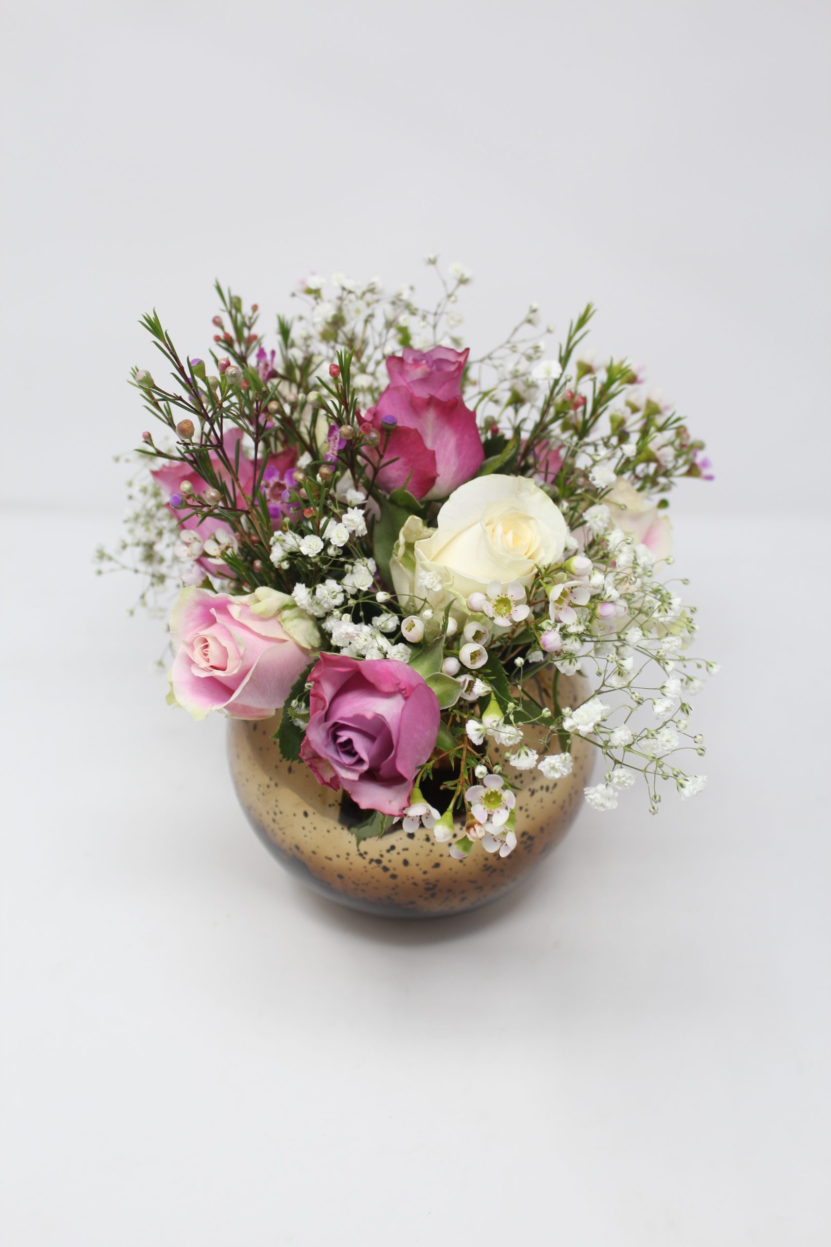 Photo of pink and yellow roses in a small bronze vase.